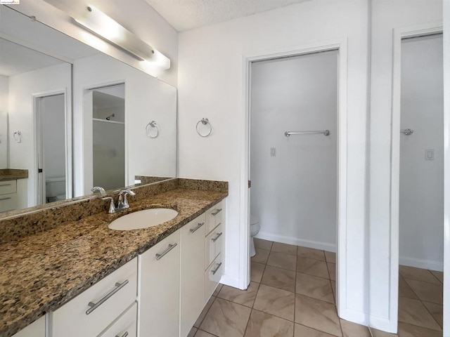 bathroom featuring toilet, walk in shower, and vanity