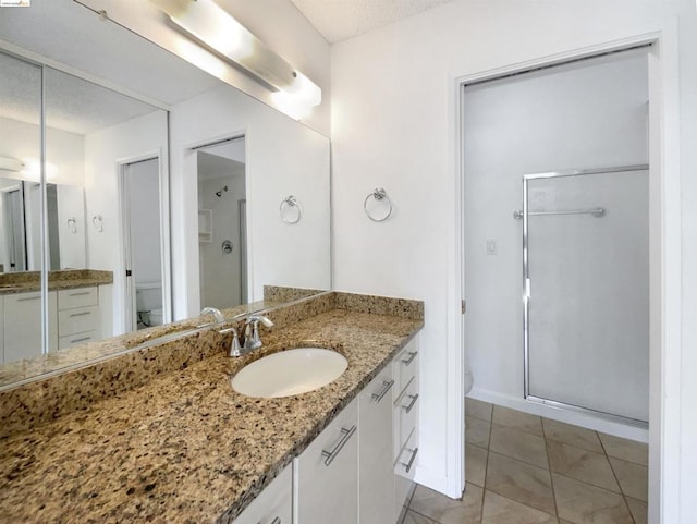 bathroom with toilet, tile patterned flooring, a shower with door, and vanity