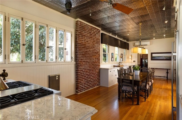 dining room with hardwood / wood-style floors, ceiling fan, and brick wall