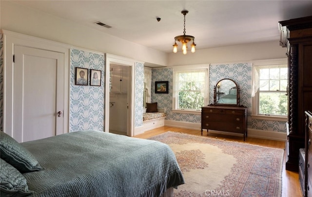 bedroom featuring multiple windows, light wood-type flooring, and a chandelier