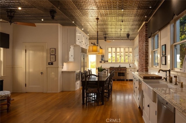 kitchen with ceiling fan, pendant lighting, stainless steel dishwasher, wood-type flooring, and white cabinetry