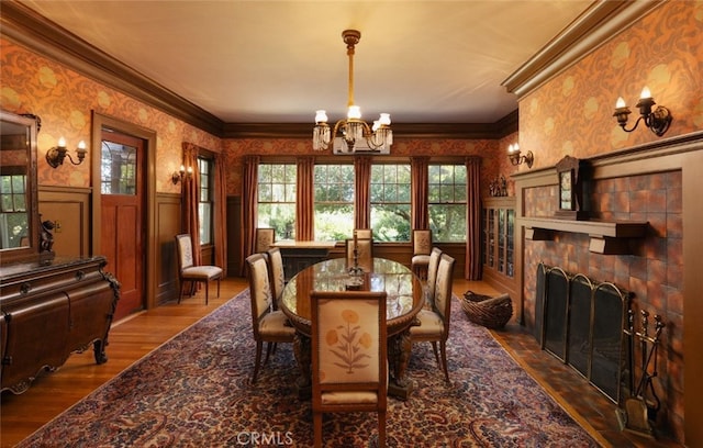 dining area with dark hardwood / wood-style floors, crown molding, a large fireplace, and a notable chandelier