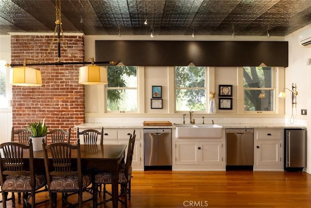 interior space featuring wood-type flooring, stainless steel dishwasher, white cabinetry, and sink