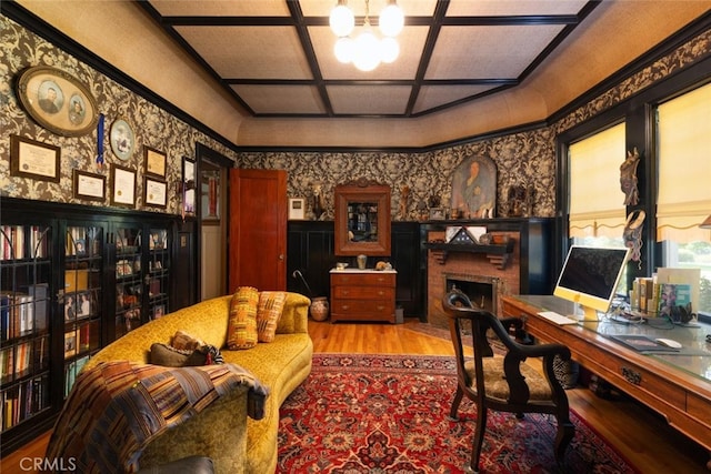 office area with light wood-type flooring, coffered ceiling, a chandelier, and a brick fireplace