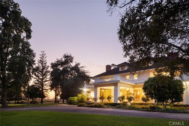 view of front facade featuring a lawn and a balcony