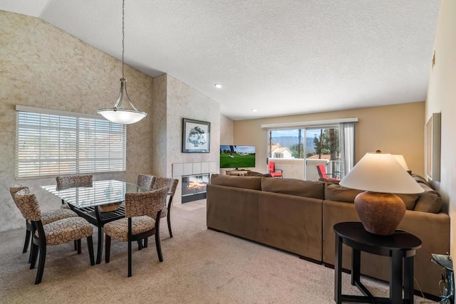 carpeted living room with a tile fireplace, a textured ceiling, and vaulted ceiling