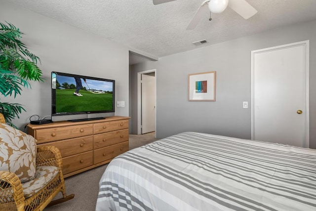 carpeted bedroom featuring ceiling fan and a textured ceiling