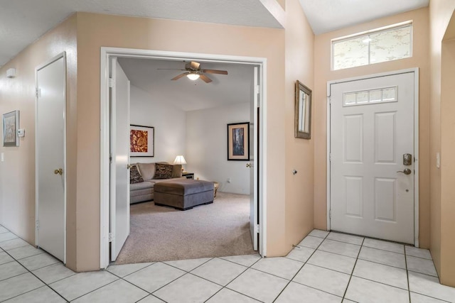 carpeted entryway featuring ceiling fan and vaulted ceiling