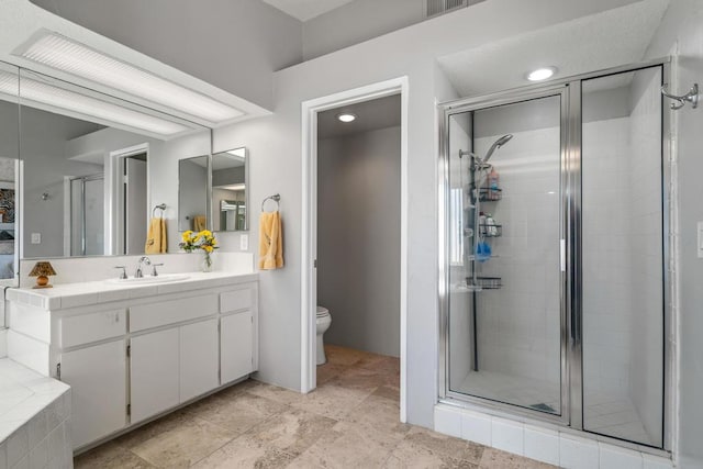 bathroom featuring a shower with door, vanity, and toilet