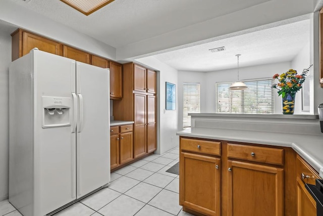 kitchen featuring a textured ceiling, white fridge with ice dispenser, light tile patterned floors, and pendant lighting