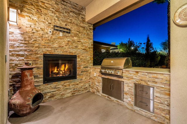 view of patio / terrace with area for grilling, an outdoor stone fireplace, and a grill