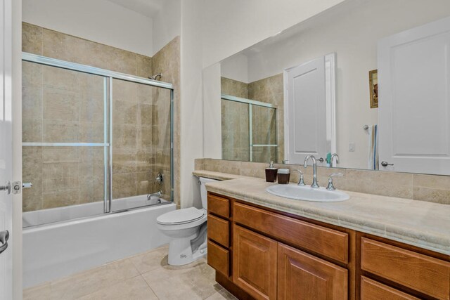 full bathroom with shower / bath combination with glass door, tile patterned flooring, vanity, and toilet