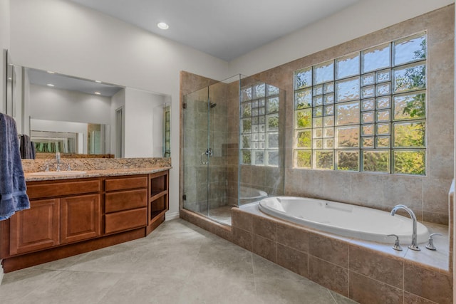 bathroom featuring plus walk in shower, tile patterned flooring, and vanity