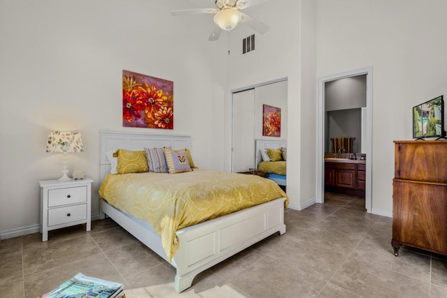 tiled bedroom featuring a closet, a high ceiling, ensuite bath, and ceiling fan