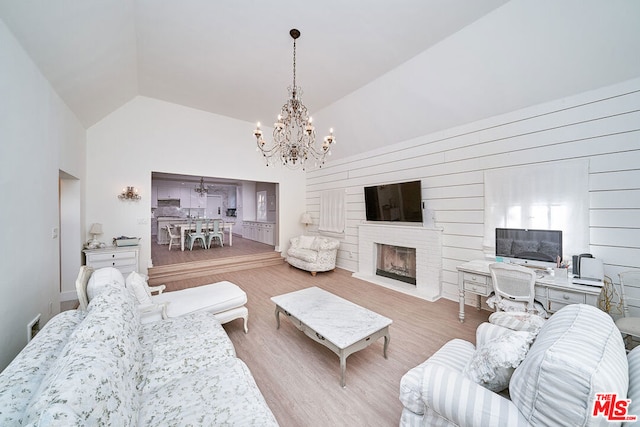 living room featuring vaulted ceiling, light hardwood / wood-style flooring, and a notable chandelier