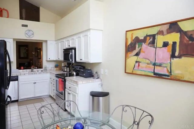 kitchen featuring appliances with stainless steel finishes, white cabinets, high vaulted ceiling, tile countertops, and sink