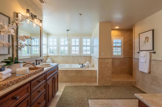 bathroom featuring tile walls, a relaxing tiled tub, and vanity