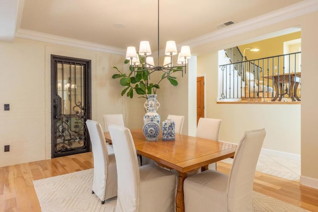 dining area with an inviting chandelier, crown molding, and light hardwood / wood-style floors