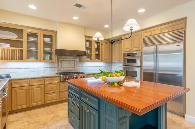 kitchen with decorative light fixtures, a kitchen island, custom exhaust hood, stainless steel appliances, and butcher block counters