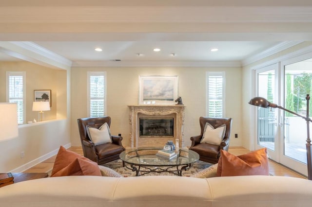 living room featuring a high end fireplace, a wealth of natural light, light hardwood / wood-style floors, and ornamental molding