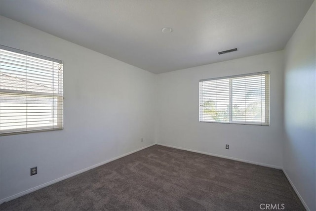 spare room featuring dark colored carpet