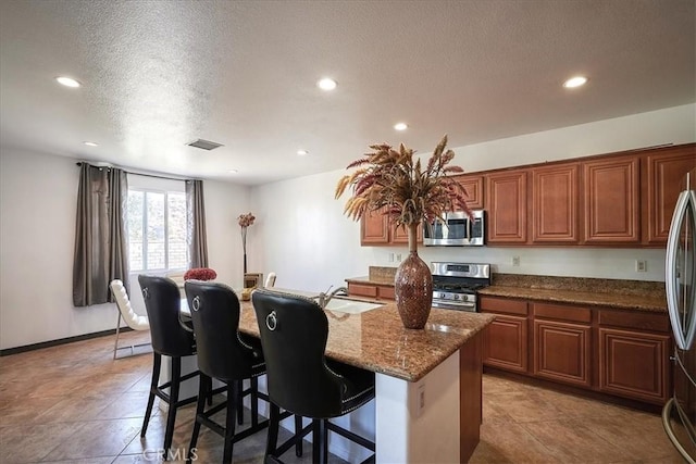 kitchen featuring sink, stone countertops, a breakfast bar area, a kitchen island with sink, and appliances with stainless steel finishes