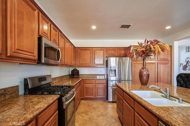 kitchen featuring light stone counters, sink, light tile patterned floors, and stainless steel appliances