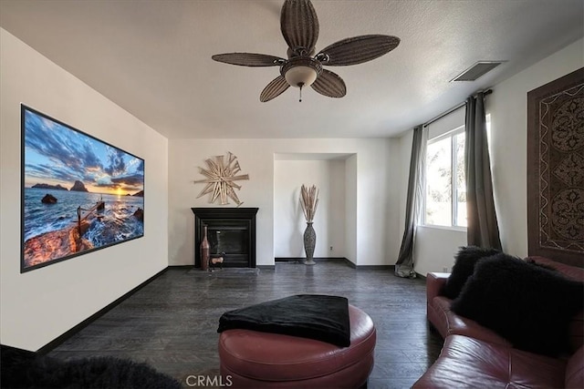 living room featuring ceiling fan, dark hardwood / wood-style flooring, and a textured ceiling