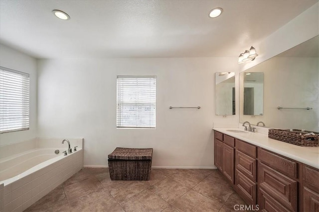 bathroom featuring tile patterned floors, tiled tub, vanity, and a healthy amount of sunlight