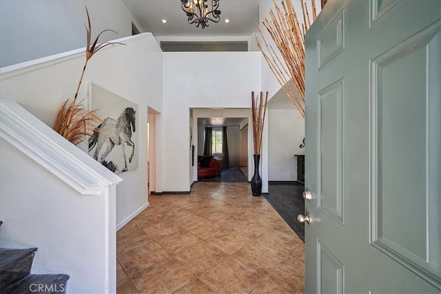 tiled foyer entrance with a towering ceiling and a notable chandelier