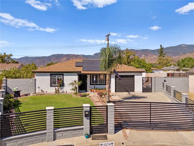 view of front facade with a garage, solar panels, a front yard, and a mountain view