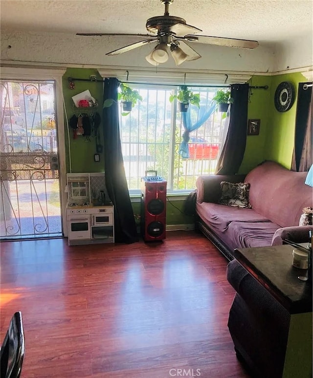 living room with a textured ceiling, hardwood / wood-style floors, and ceiling fan