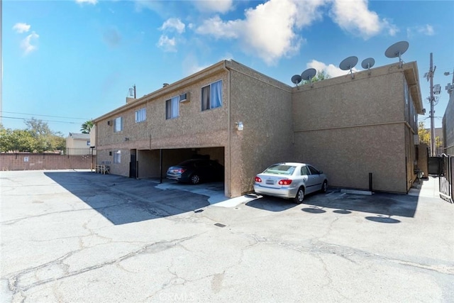 view of property exterior with fence, uncovered parking, and stucco siding