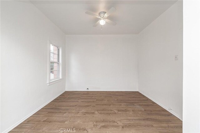 spare room featuring baseboards, ceiling fan, and wood finished floors
