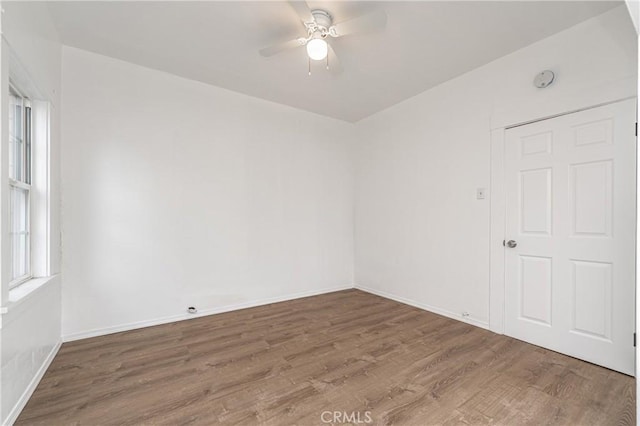 unfurnished room with baseboards, a ceiling fan, and wood finished floors