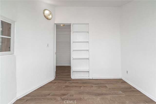 empty room featuring dark wood-style floors and baseboards