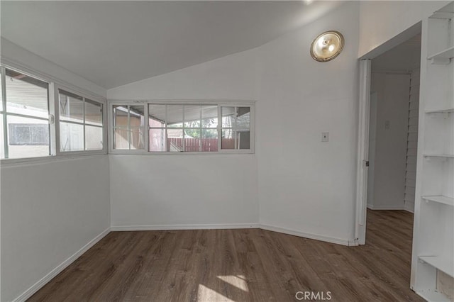 spare room with lofted ceiling, dark wood-style flooring, and baseboards