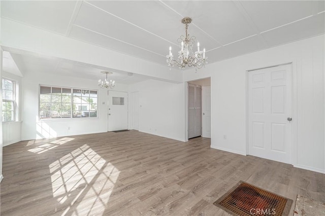 unfurnished living room with an inviting chandelier, baseboards, visible vents, and light wood finished floors