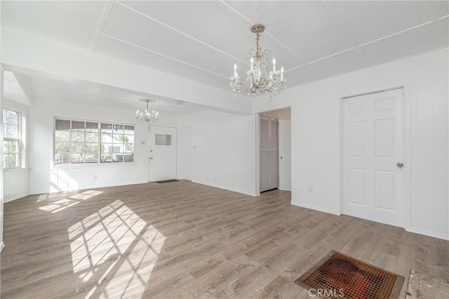 unfurnished living room featuring baseboards, an inviting chandelier, and wood finished floors