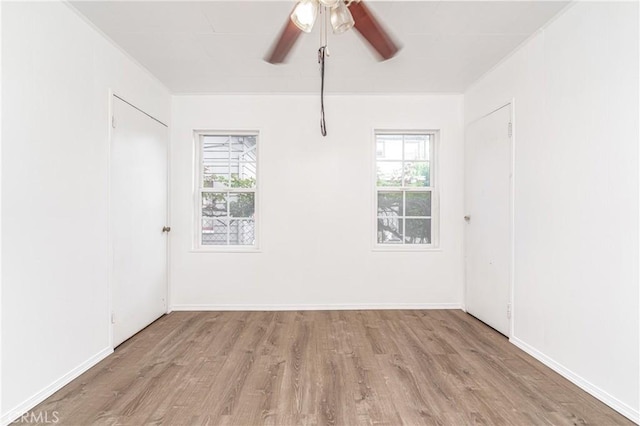 empty room featuring light wood-style floors, baseboards, and a ceiling fan