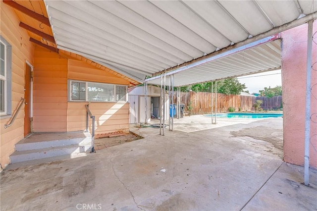 view of patio featuring an outbuilding, a shed, a fenced backyard, and a fenced in pool