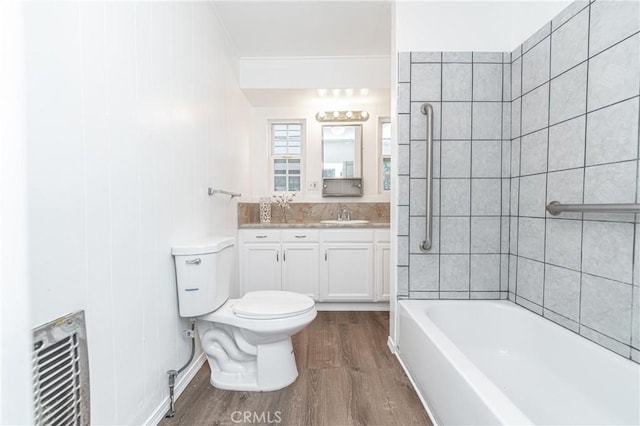 bathroom with toilet, wood finished floors, shower / bathing tub combination, and vanity