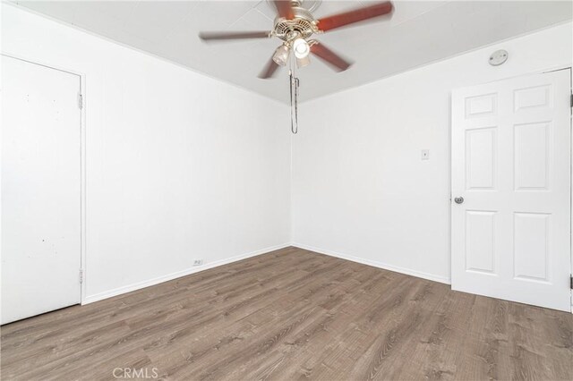 spare room with baseboards, a ceiling fan, and wood finished floors