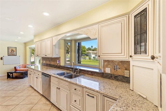 kitchen featuring light stone counters, stainless steel dishwasher, a wealth of natural light, and sink