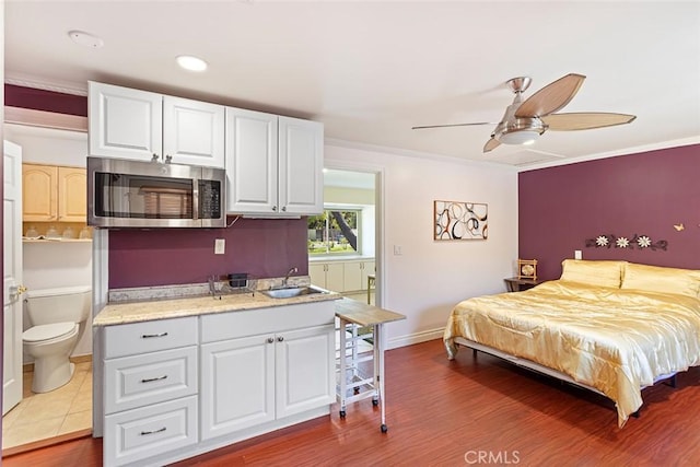 bedroom featuring ensuite bath, ceiling fan, sink, crown molding, and hardwood / wood-style floors