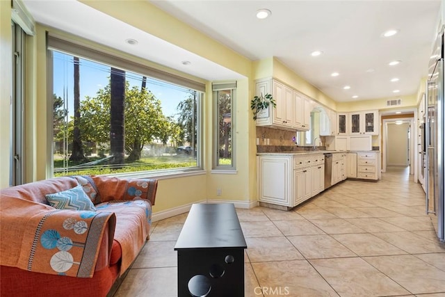 kitchen with dishwasher, light tile patterned floors, white cabinetry, and sink