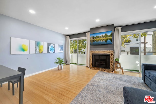 living room featuring wood-type flooring, a wealth of natural light, and a tile fireplace