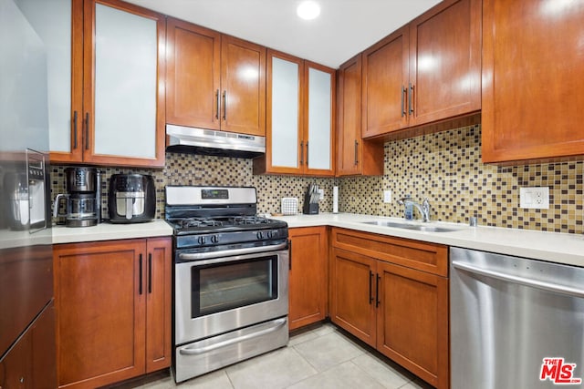 kitchen with appliances with stainless steel finishes, decorative backsplash, light tile patterned flooring, and sink