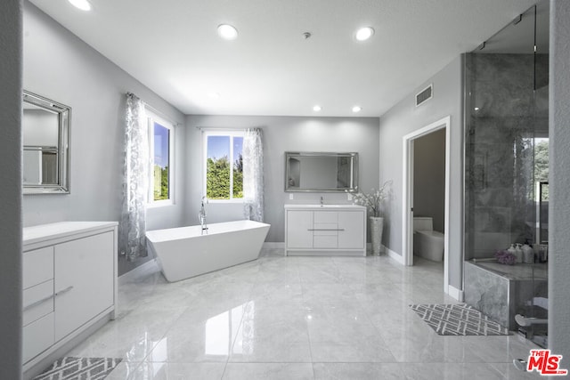 bathroom featuring vanity, toilet, and a tub to relax in