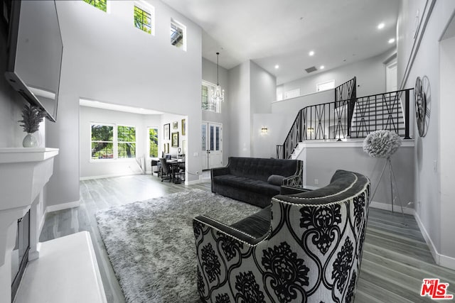 living room featuring wood-type flooring, a high ceiling, and an inviting chandelier